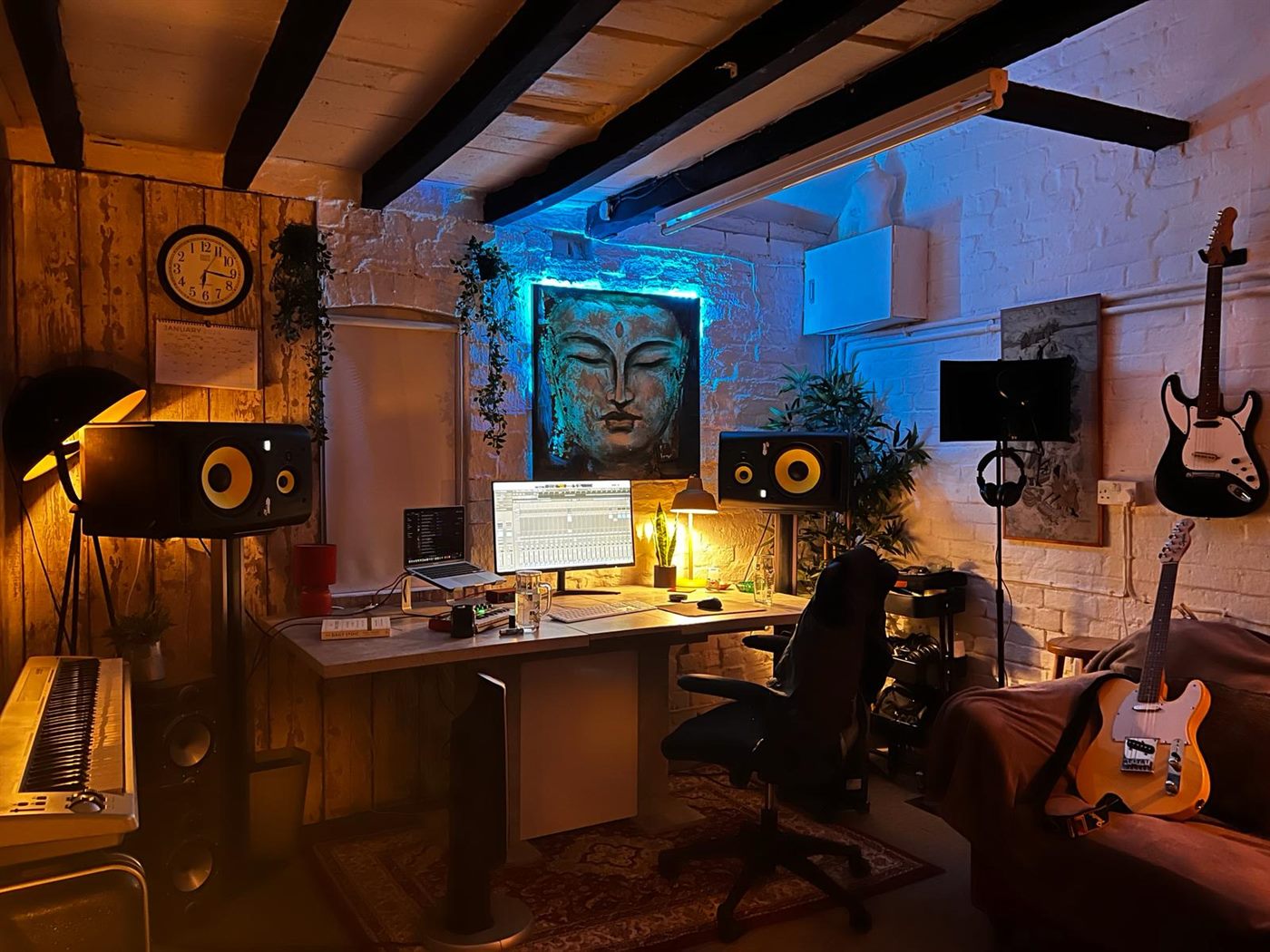 The control room at night, lit by warm lamps and a strip of blue light behind the artwork.