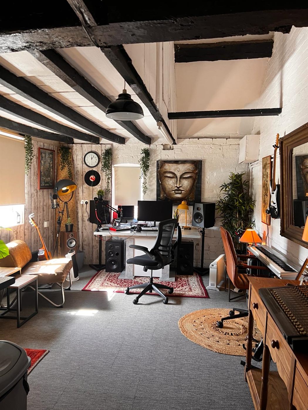 The full length of the studio in daylight: desk and monitors at the far end, sofa and coffee table in the foreground.