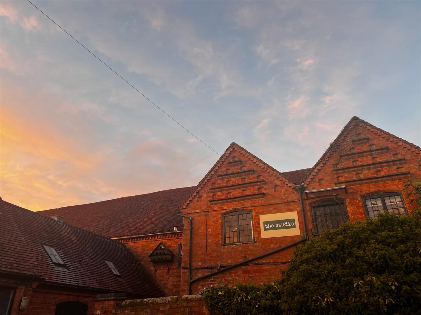 The red-brick building at sunset with the studio sign on the gable end.